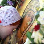 A girl bows to the icon of the Mother of God